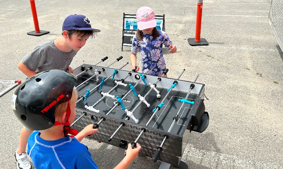 Three kids playing foosball outside