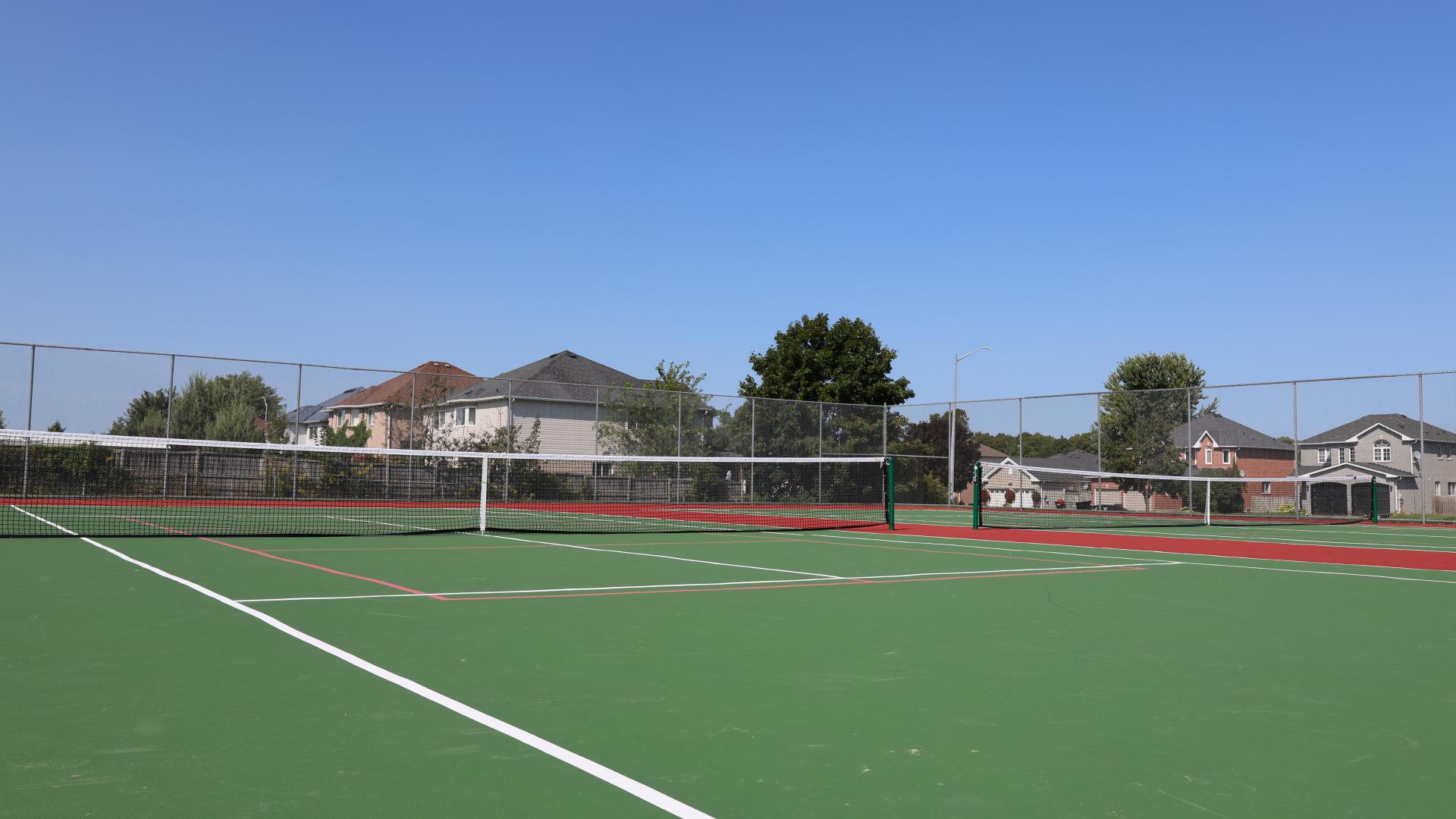 Two tennis courts with houses in the background