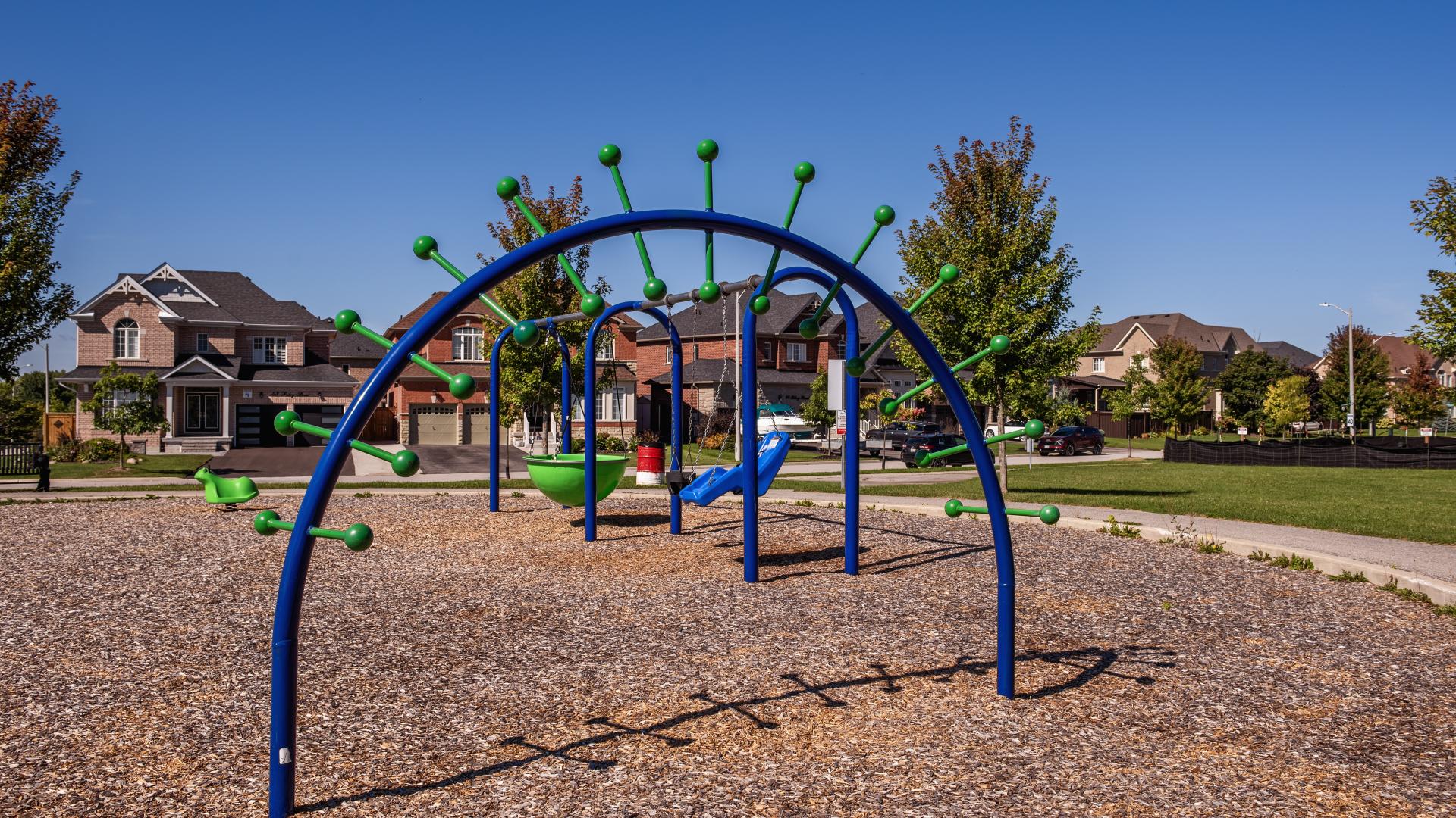 Spiraling free standing monkey bar in a children's playground and suburban houses in the background