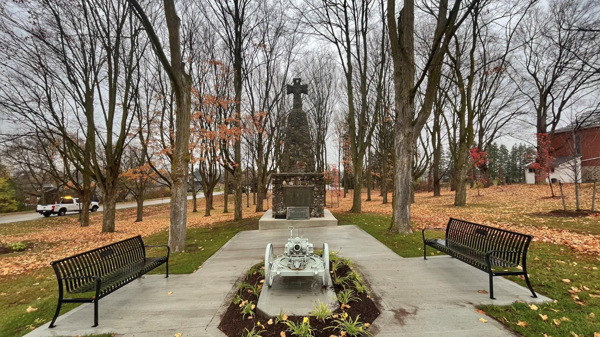 Cenotaph at the end of a pathway surrounded by autumn trees; the branches bare and the leaves on the ground