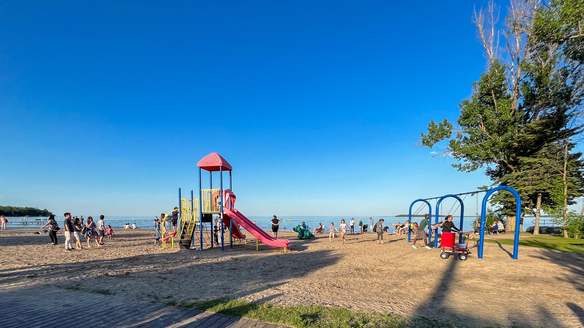 Kids using playground and swing set at a beach park on a sunny day