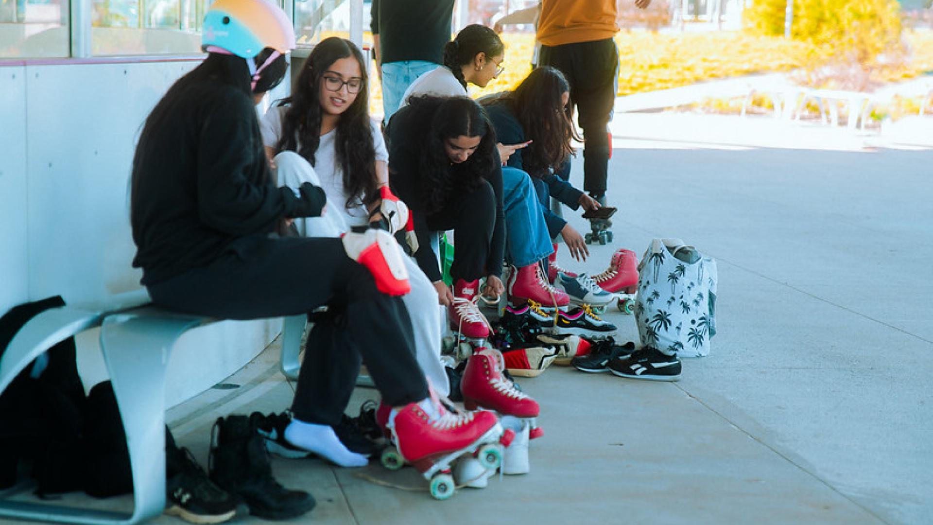 Teens putting on roller skates outside