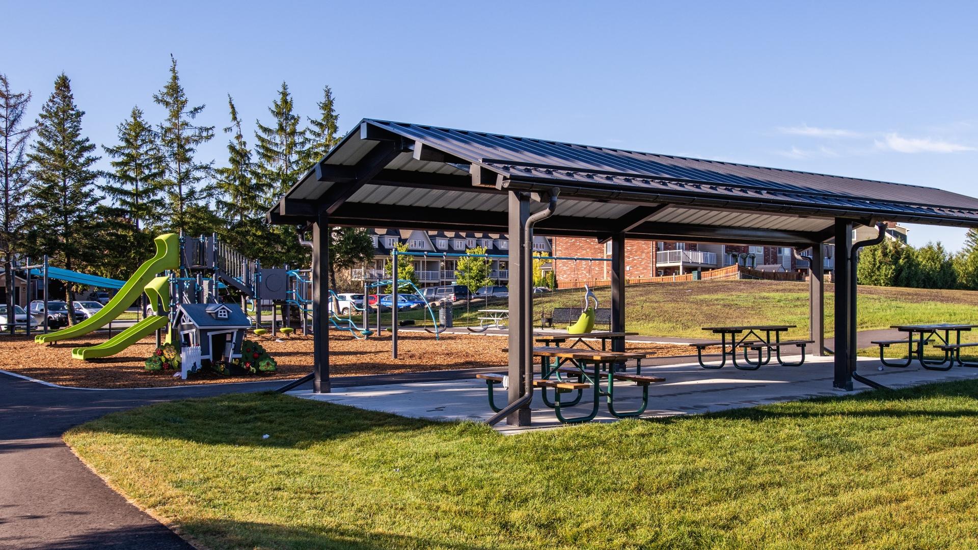 Modern children's playground with slides, swings, and other elements with a suburban neighbourhood in the background