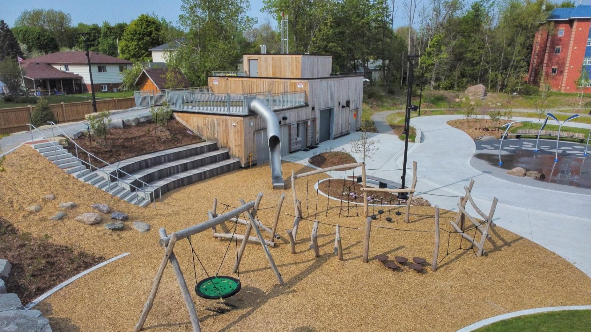 Aerial shot of park with large slide, natural playground elements and splash pad
