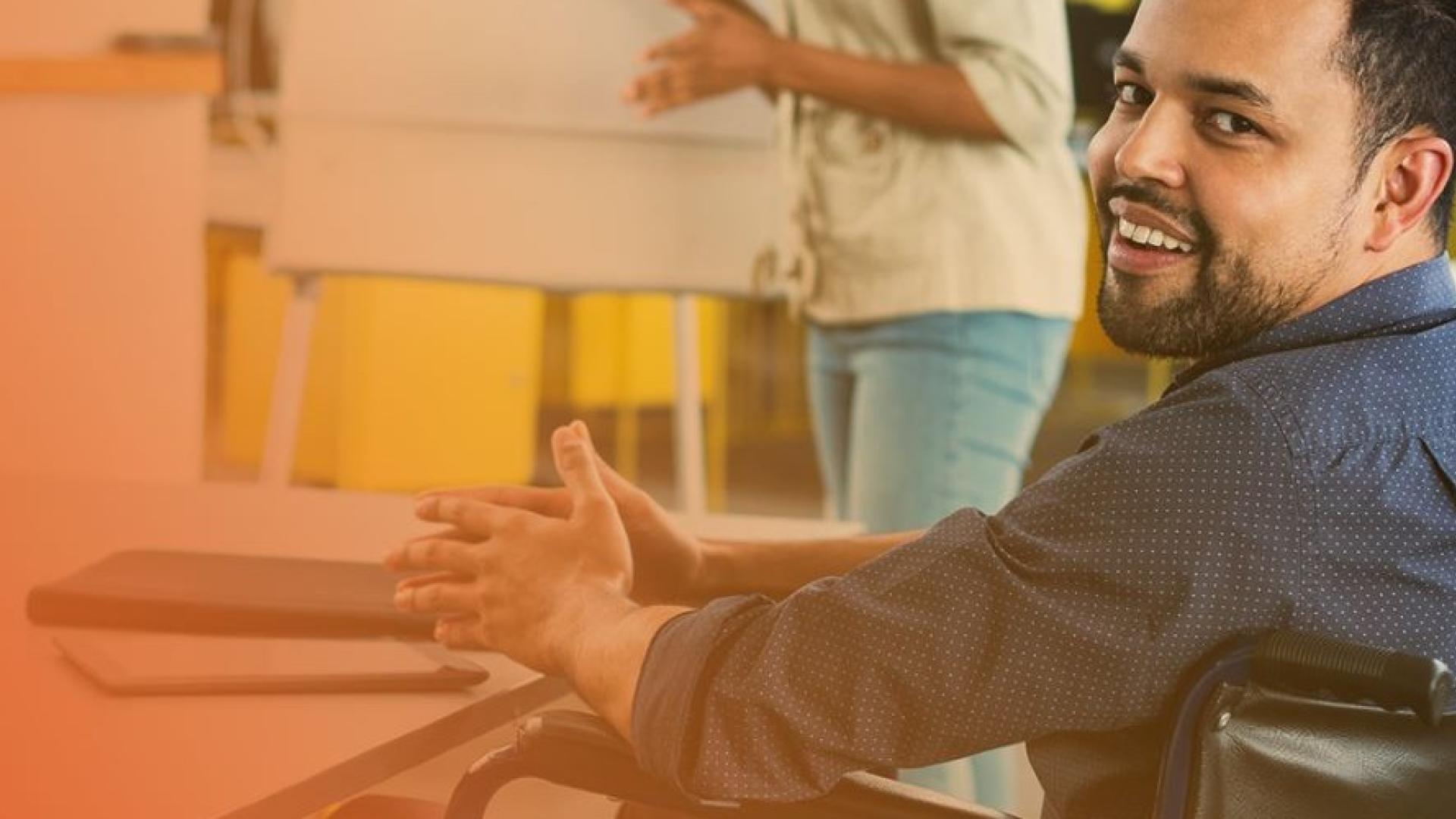 Man in wheelchair at desk smiling