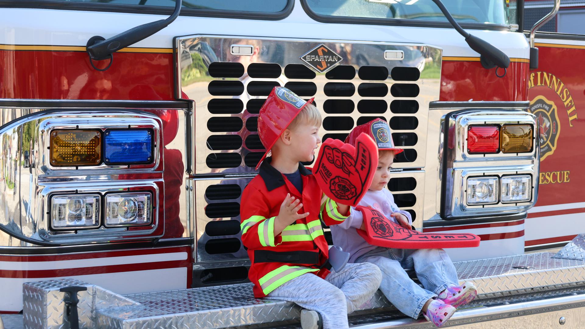 Two kids sitting on top of fire truck