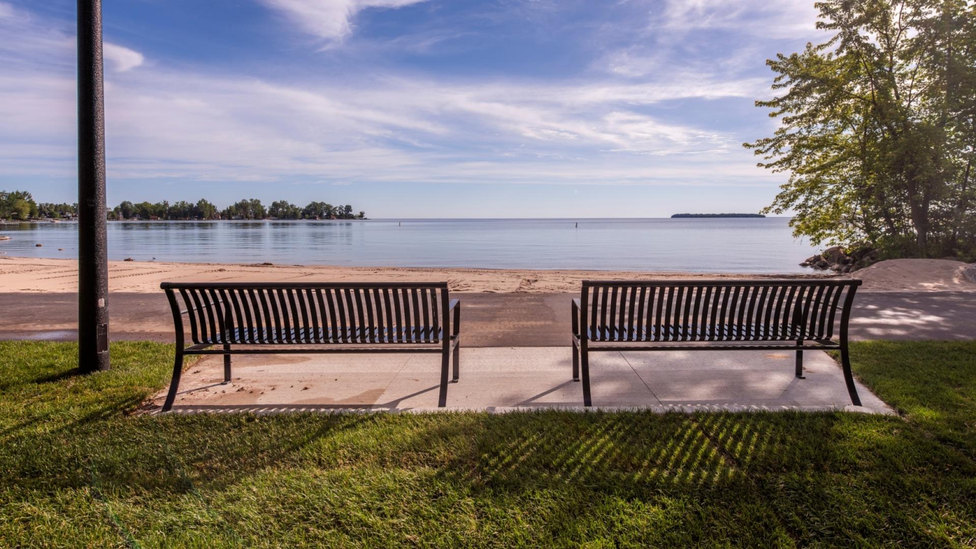 Two benches with lake and sandy beach in front