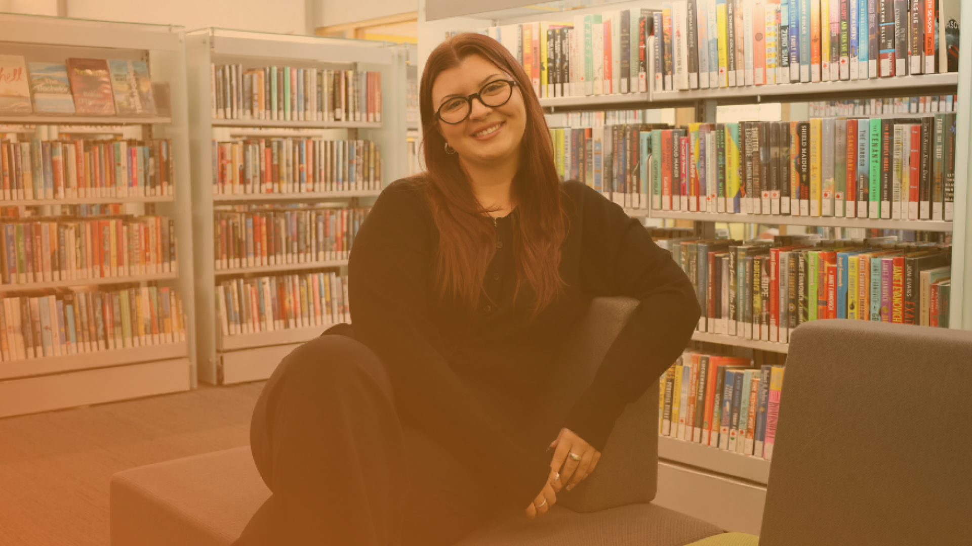 female employee smiling while seated at the library