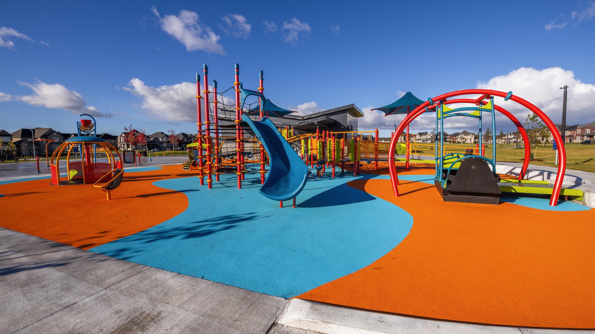 Wide view of Margaretta Park’s inclusive playground with accessible swings, slides, climbing structures, and colourful rubber safety surfacing.