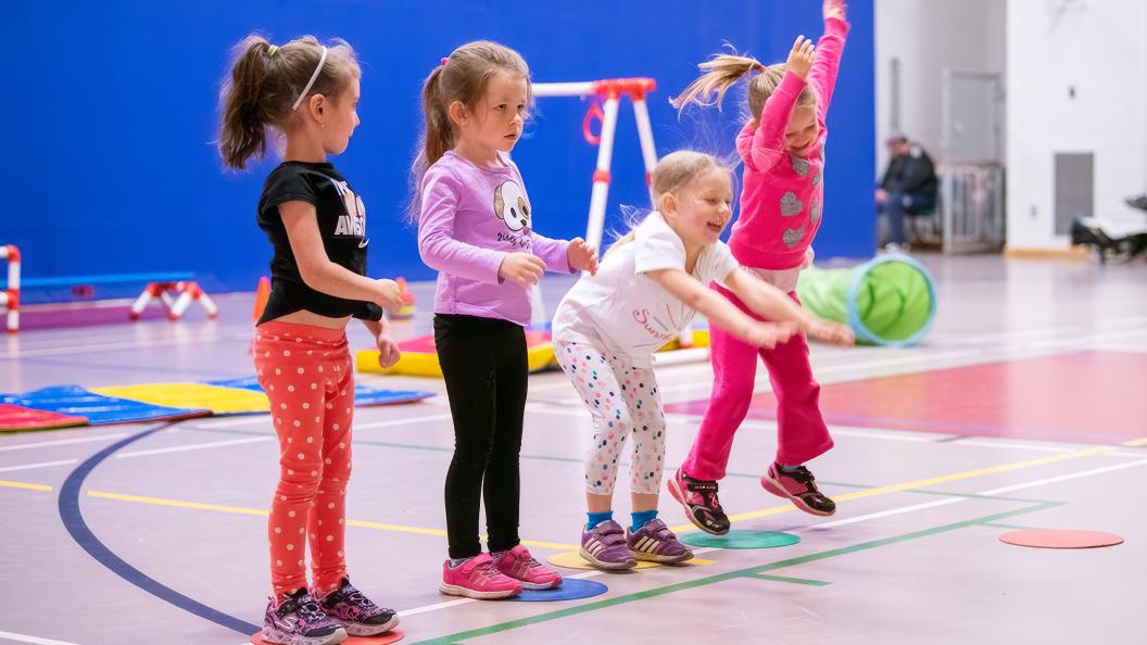 Four young children jumping in gym during recreation program