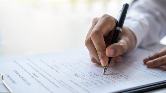 Close-up of a person writing on a clipboard