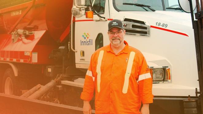 smiling road operator standing in front of large truck