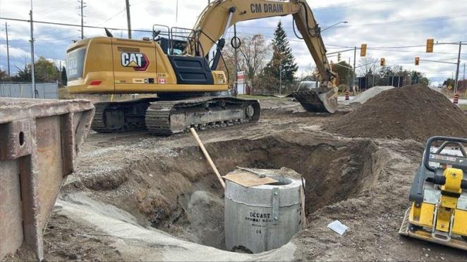 Large construction machine near road work with pipes exposed