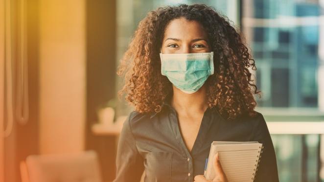 Happy woman with curly hair smiling behind face covering