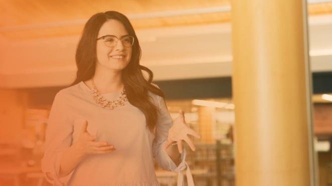 Woman with dark hair smiling with hands up
