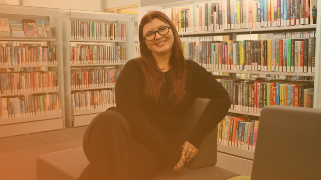 female employee smiling while seated at the library