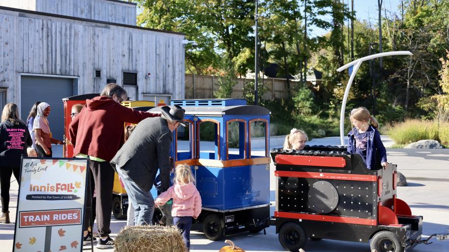 Children with guardians climbing into a trackless train ride