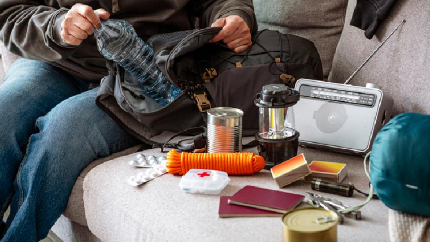 Woman filling emergency backpack with disaster emergency supplies