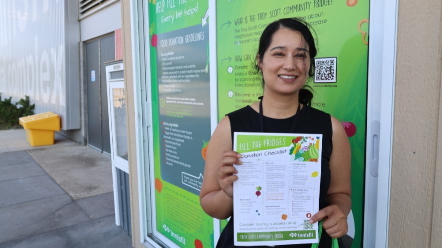 Woman holding donation checklist at community fridge