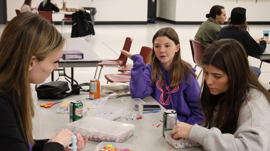 Three teen girls making beaded friendship bracelets