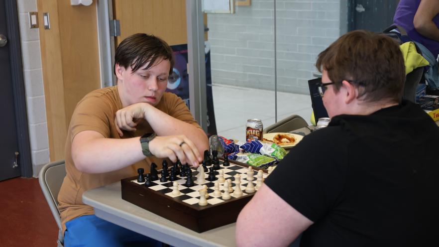 Teen boy and Teen Nights staff playing chess