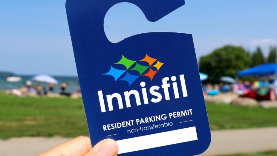 Woman holding up Innisfil resident parking pass at beach