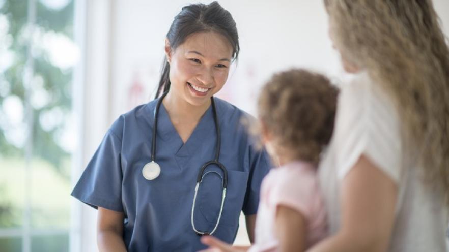 Nurse speaking to girl and mother at checkup appointment.