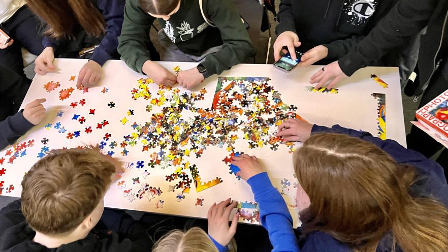 Group of teens building a jigsaw puzzle