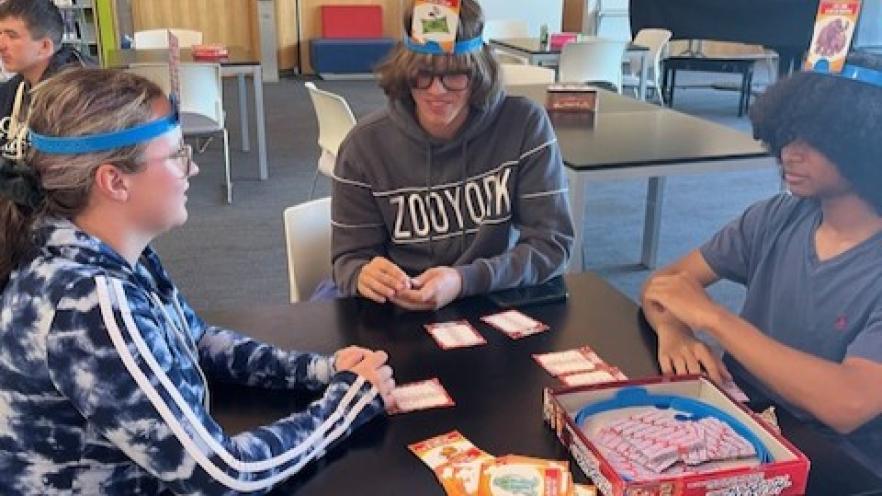 Three teens playing a card game at Teen Nights