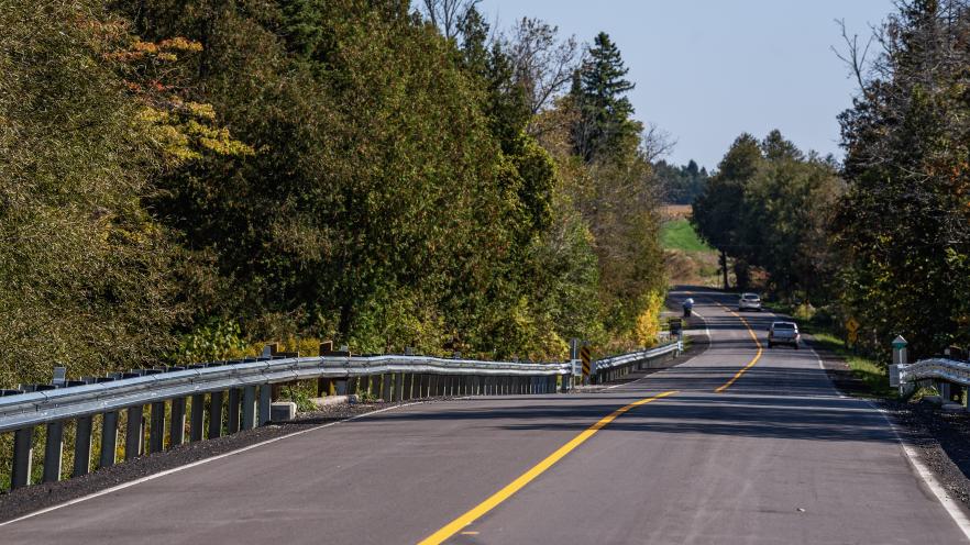 Two cars driving down freshly paved rural road