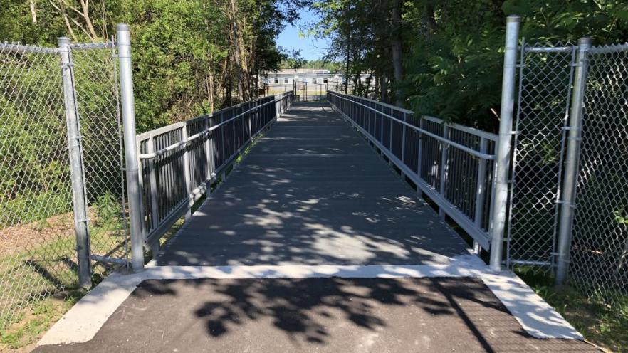 Fenced in trail with trees on either side 