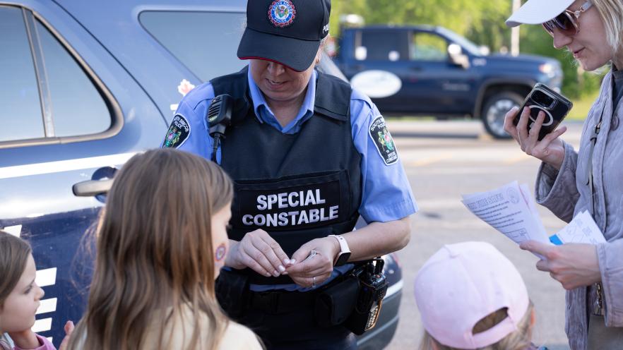 Police officer giving stickers to children at community event