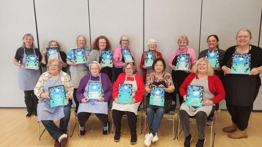 Group of seniors posing in a seated position showing their artwork