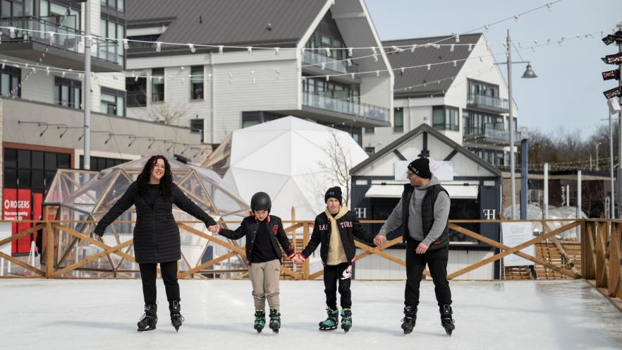 Mom, dad and two children ice skating on promenade at Friday Harbour