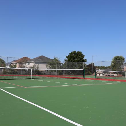 Two tennis courts with houses in the background