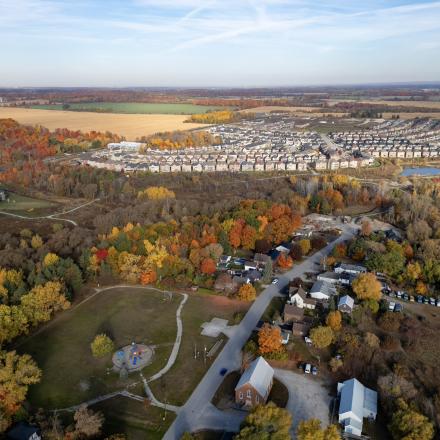 Arial view of a green space in the middle of landscape with forests and suburban developments