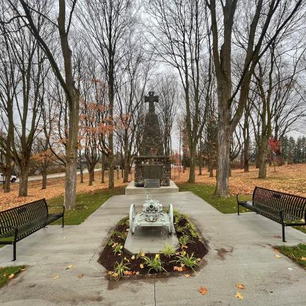 Cenotaph at the end of a pathway surrounded by autumn trees; the branches bare and the leaves on the ground