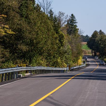 Two cars driving down freshly paved rural road