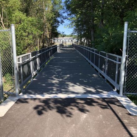 Fenced in trail with trees on either side 