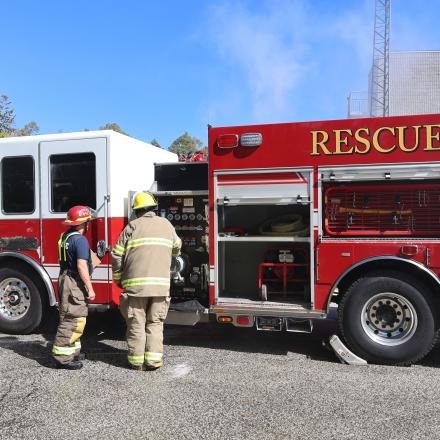 Two firefighters standing by fire truck