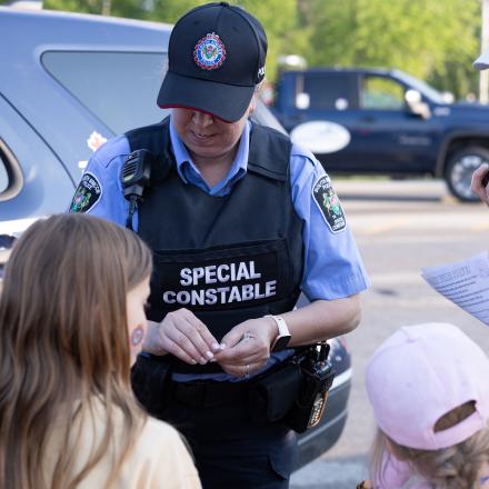 Police officer giving stickers to children at community event