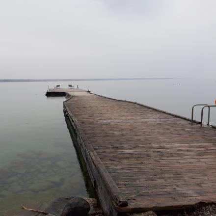 Wooden dock extending into an overcast Lake Simcoe