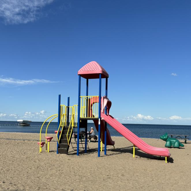 Playground on sandy beach with lake in the background