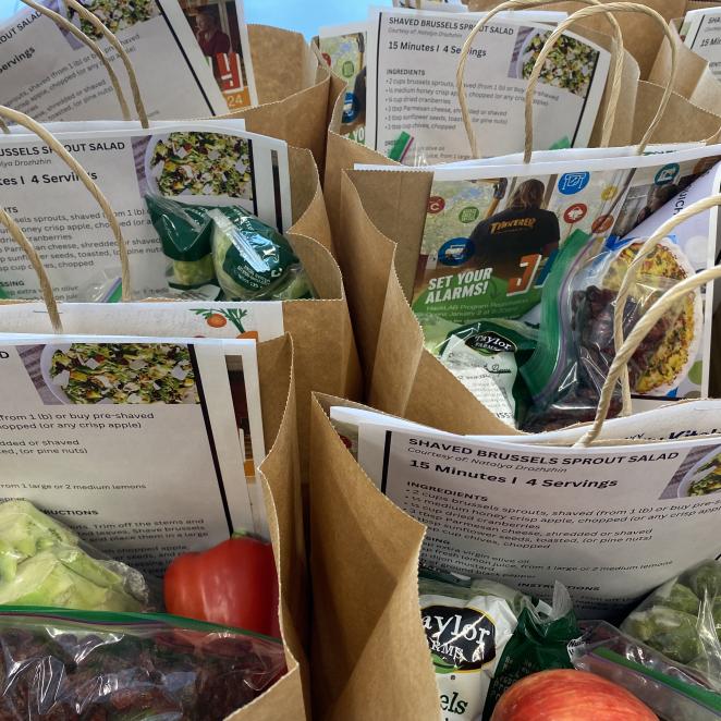 Multiple paper bags with a printed paper that read "Senior Meal Kits" stapled to the outside