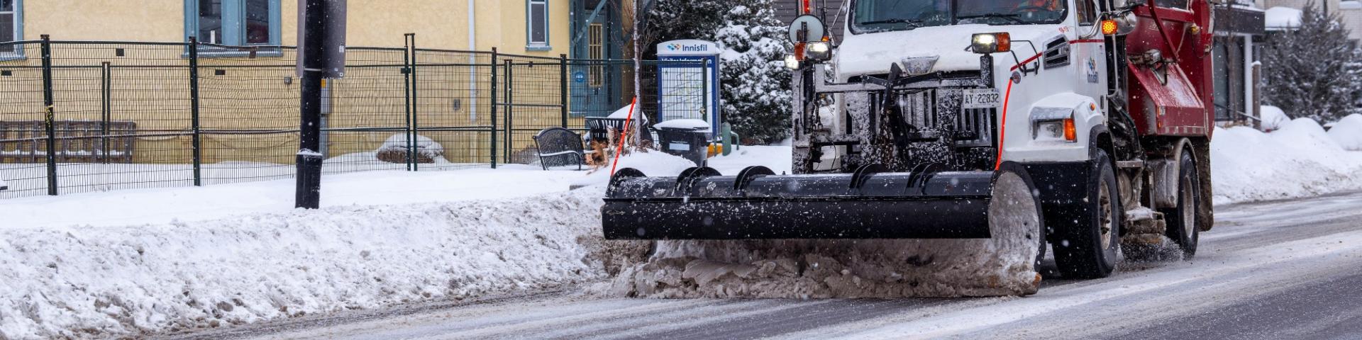 Snowplow plowing street on snowy day in Cookstown