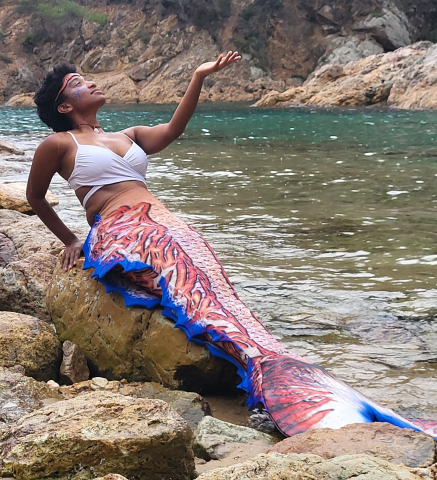 Mermaid basking on rocks next to a river