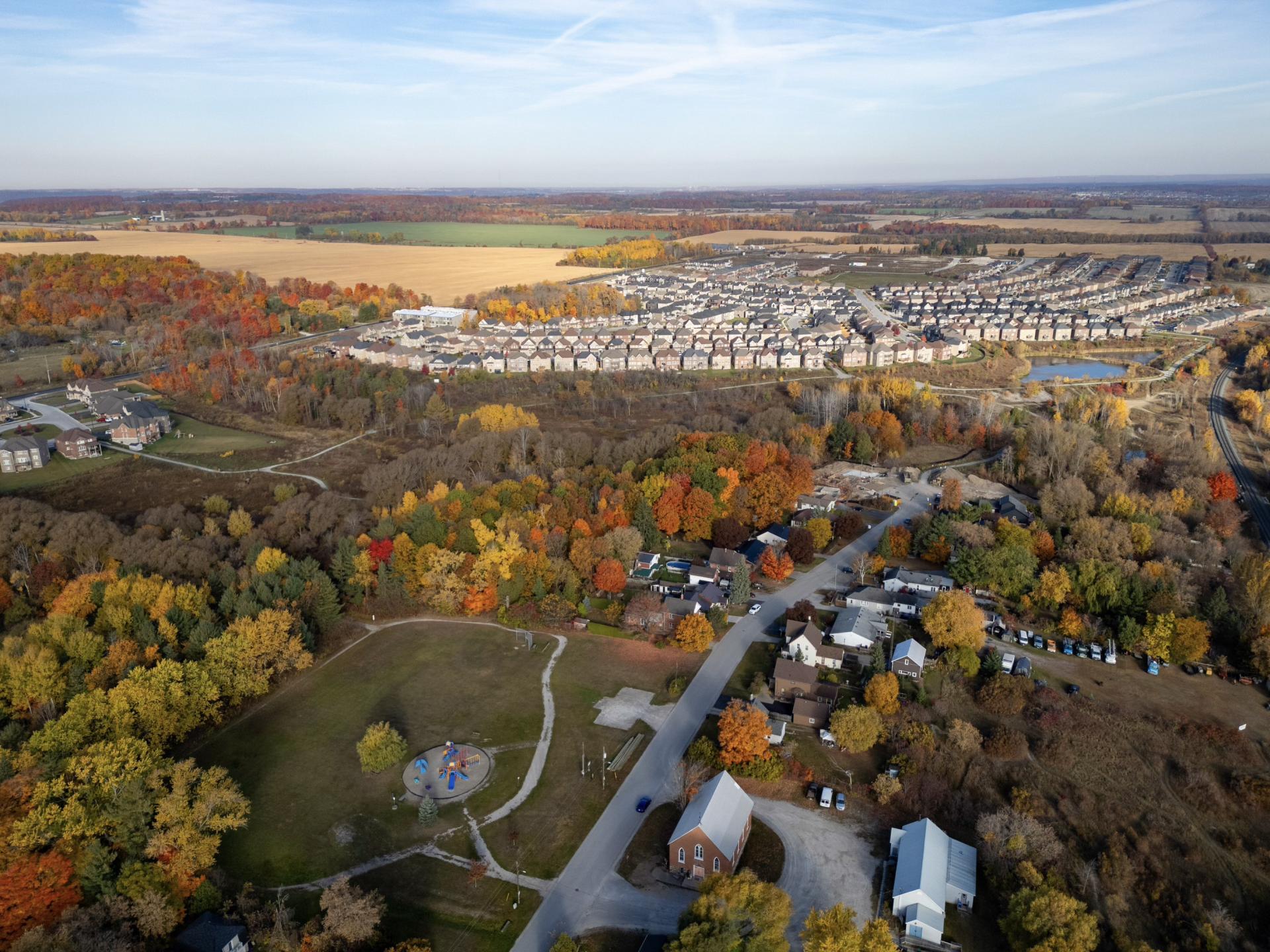 Arial view of a green space in the middle of landscape with forests and suburban developments